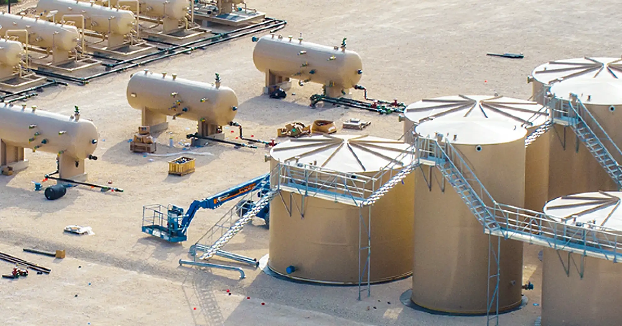 Aerial view of a well pad showing multiple horizontal production separators and storage tanks under construction